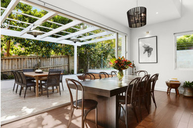 This is an example of a mid-sized contemporary open plan dining in Sydney with white walls, medium hardwood floors and brown floor.