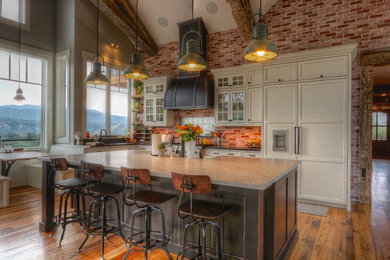 Inspiration for a large country l-shaped eat-in kitchen in Denver with a farmhouse sink, black cabinets, granite benchtops, black splashback, panelled appliances, with island, brown floor, black benchtop, medium hardwood floors and beaded inset cabinets.