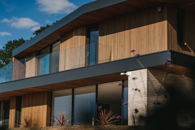 Photo of a large contemporary two-storey house exterior in Hampshire with a flat roof.
