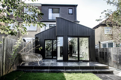 Foto på ett mellanstort funkis svart flerfamiljshus, med tre eller fler plan, blandad fasad, sadeltak och tak i mixade material