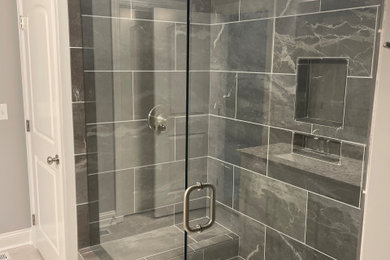 Mid-sized master ceramic tile and beige floor shower bench photo in Nashville with gray walls and a hinged shower door
