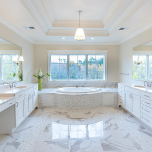 Example of a large transitional master beige tile and stone tile porcelain tile, white floor, double-sink and tray ceiling drop-in bathtub design in DC Metro with recessed-panel cabinets, white cabinets, beige walls, an undermount sink, quartz countertops, white countertops and a built-in vanity