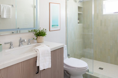 Beach style gray tile and ceramic tile porcelain tile, green floor and single-sink bathroom photo in Santa Barbara with flat-panel cabinets, a one-piece toilet, white walls, an undermount sink, quartz countertops, white countertops, a built-in vanity and medium tone wood cabinets