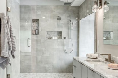 Example of a large minimalist master gray tile and porcelain tile porcelain tile and gray floor alcove shower design in Dallas with flat-panel cabinets, gray cabinets, a two-piece toilet, gray walls, a drop-in sink, marble countertops, a hinged shower door and gray countertops