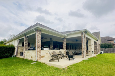 Patio - huge transitional backyard concrete patio idea in Houston with a fireplace and a roof extension