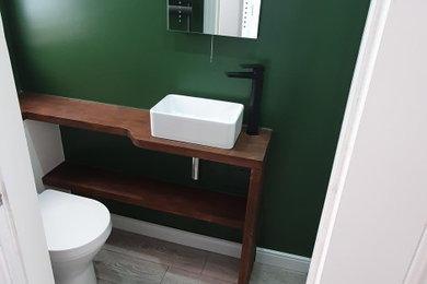 Design ideas for a small contemporary bathroom in Surrey with flat-panel cabinets, white cabinets, a walk-in shower, a one-piece toilet, green walls, laminate floors, a trough sink, wooden worktops, grey floors, a hinged door, brown worktops, a single sink and a built in vanity unit.