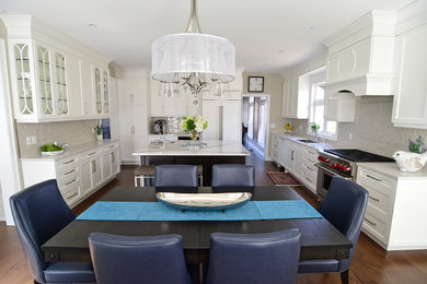 Kitchen - transitional medium tone wood floor and brown floor kitchen idea with a double-bowl sink, recessed-panel cabinets, white cabinets, quartz countertops, gray backsplash, ceramic backsplash, paneled appliances, an island and gray countertops