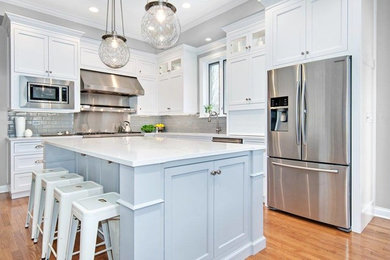 Mid-sized transitional l-shaped light wood floor and beige floor kitchen photo in Chicago with an undermount sink, shaker cabinets, white cabinets, quartzite countertops, gray backsplash, subway tile backsplash, stainless steel appliances and an island