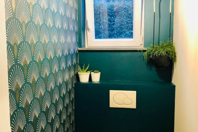 Réalisation d'un petit WC suspendu design avec un placard à porte affleurante, des portes de placard noires, un mur vert, un sol en carrelage de céramique, un lavabo encastré, un sol gris, un plan de toilette blanc, meuble-lavabo suspendu et du papier peint.