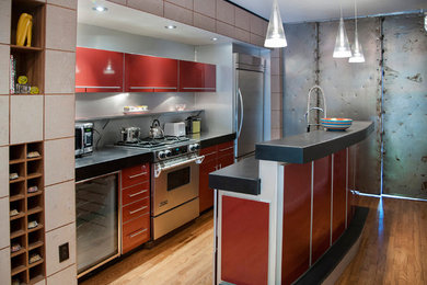 Design ideas for an industrial single-wall open plan kitchen in New York with an undermount sink, flat-panel cabinets, red cabinets, granite benchtops, grey splashback and stainless steel appliances.