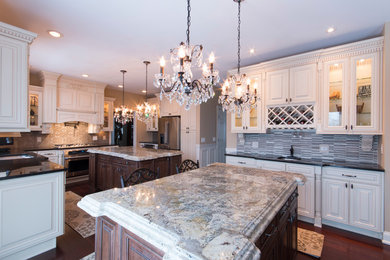 Example of a classic eat-in kitchen design in New York with an undermount sink, raised-panel cabinets, granite countertops, blue backsplash, glass tile backsplash and stainless steel appliances