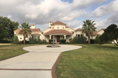 Large tuscan beige two-story stucco house exterior photo in Austin with a hip roof and a tile roof