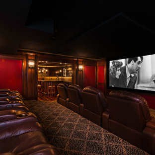 Exemple d'une grande salle de cinéma chic fermée avec un mur rouge, moquette, un écran de projection et un sol multicolore.
