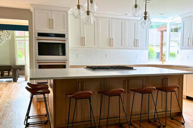 Large transitional u-shaped medium tone wood floor eat-in kitchen photo in Seattle with an undermount sink, shaker cabinets, white cabinets, quartz countertops, white backsplash, subway tile backsplash, white appliances, an island and white countertops