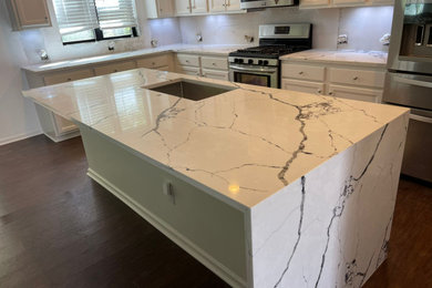 Example of a minimalist eat-in kitchen design in Raleigh with an undermount sink, quartz countertops, white backsplash, an island and multicolored countertops