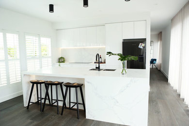 Inspiration for a modern open plan kitchen in Melbourne with a double-bowl sink, white cabinets, marble benchtops, white splashback, marble splashback, black appliances, with island and white benchtop.