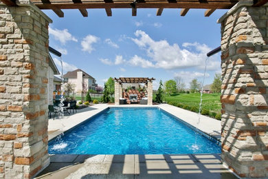 Photo of a mid-sized contemporary backyard rectangular lap pool in St Louis with a water feature and stamped concrete.