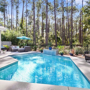 Idéer för mellanstora vintage l-formad träningspooler på baksidan av huset, med en fontän och granitkomposit