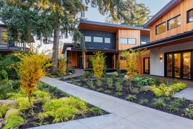 Example of a trendy two-story wood and clapboard house exterior design in Portland with a shed roof, a metal roof and a black roof