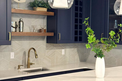 Wet bar - mid-sized transitional u-shaped vinyl floor wet bar idea in Other with an undermount sink, flat-panel cabinets, blue cabinets, quartz countertops, beige backsplash, mosaic tile backsplash and beige countertops