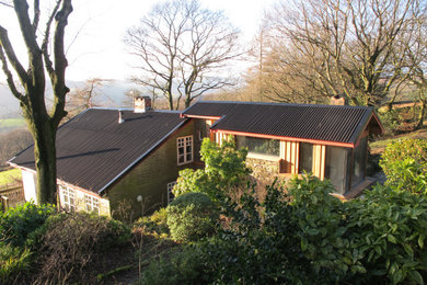 Modelo de fachada de casa marrón y negra contemporánea de tamaño medio de dos plantas con revestimiento de madera, tejado a dos aguas y tejado de metal