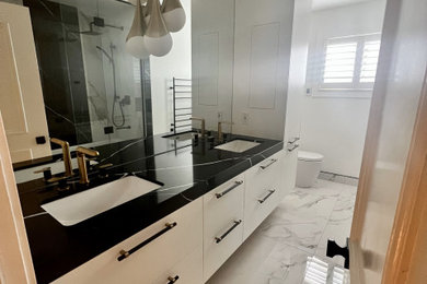 Example of a small trendy black and white tile and marble tile marble floor, white floor and double-sink bathroom design in Toronto with flat-panel cabinets, white cabinets, a one-piece toilet, white walls, an undermount sink, marble countertops, black countertops, a niche and a floating vanity