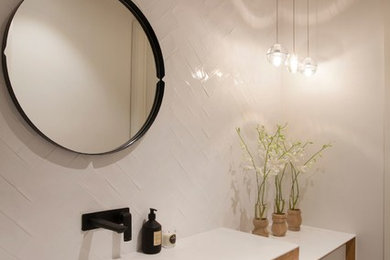 Inspiration for a contemporary powder room in Melbourne with an integrated sink, white tile and white benchtops.