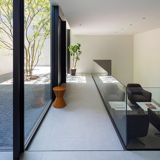 Photo of a modern home office and library in Tokyo with white walls, a freestanding desk and grey floors.