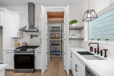 Inspiration for a mid-sized timeless l-shaped light wood floor kitchen remodel in Houston with an undermount sink, raised-panel cabinets, white cabinets, quartz countertops, white backsplash, porcelain backsplash, stainless steel appliances, an island and white countertops