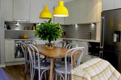 Photo of a mid-sized scandinavian l-shaped open plan kitchen in Canberra - Queanbeyan with an undermount sink, grey cabinets, quartz benchtops, grey splashback, ceramic splashback, vinyl floors, no island, brown floor and white benchtop.