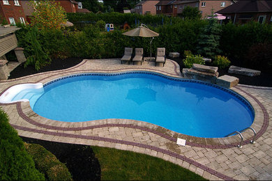 Example of a mid-sized transitional backyard concrete paver and custom-shaped lap pool design in Toronto