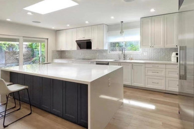 Eat-in kitchen - large modern l-shaped light wood floor and brown floor eat-in kitchen idea in Hawaii with shaker cabinets, white cabinets, solid surface countertops, gray backsplash, matchstick tile backsplash, stainless steel appliances, an island and white countertops