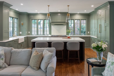 Large transitional u-shaped dark wood floor and brown floor kitchen pantry photo in Atlanta with a farmhouse sink, flat-panel cabinets, green cabinets, quartzite countertops, green backsplash, wood backsplash, paneled appliances, an island and white countertops