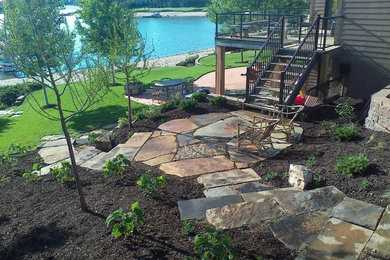 Design ideas for a mid-sized traditional backyard garden in Omaha with natural stone pavers.