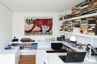 Example of a mid-sized eclectic built-in desk light wood floor study room design in Other with white walls