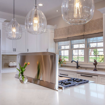Designer white kitchen with walnut island Ceasarstone counter tops down draft wi