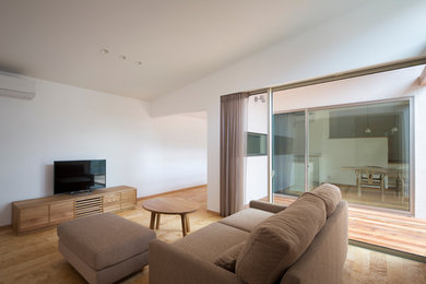 Photo of a contemporary living room in Osaka with white walls, light hardwood floors, a freestanding tv and beige floor.