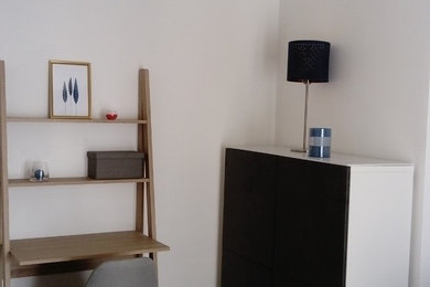 Idée de décoration pour un petit salon minimaliste fermé avec un mur gris, sol en stratifié, aucune cheminée, un téléviseur indépendant et un sol marron.