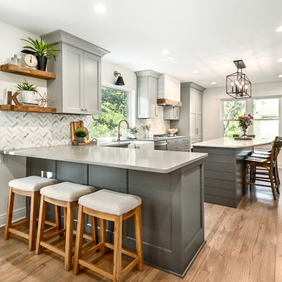 Inspiration for a huge farmhouse l-shaped medium tone wood floor and brown floor eat-in kitchen remodel in Milwaukee with a farmhouse sink, shaker cabinets, gray cabinets, quartz countertops, white backsplash, marble backsplash, stainless steel appliances, an island and gray countertops