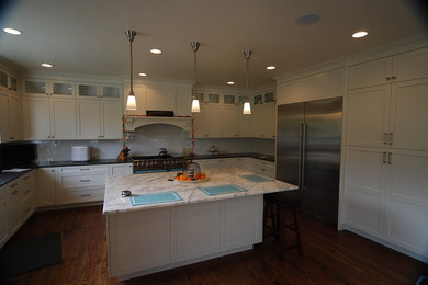 Large u-shaped medium tone wood floor eat-in kitchen photo in Seattle with white cabinets, white backsplash, stainless steel appliances and an island