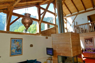 Example of a huge mountain style open concept medium tone wood floor living room design in Sussex with multicolored walls, a wood stove, a stone fireplace and a wall-mounted tv