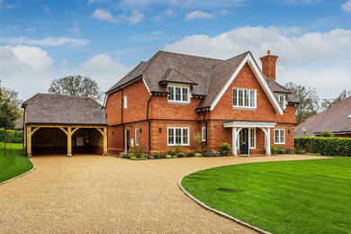 Design ideas for an expansive traditional red house exterior in Surrey.