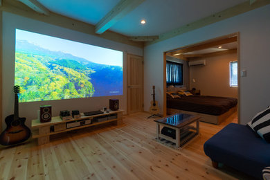 Modelo de cine en casa de estilo zen con paredes blancas, suelo de madera clara y pantalla de proyección