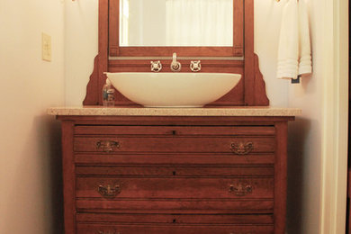 Example of a mid-sized classic master medium tone wood floor and brown floor bathroom design in Cleveland with raised-panel cabinets, dark wood cabinets, a two-piece toilet, gray walls, a vessel sink and beige countertops