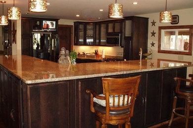 This is an example of a mid-sized traditional u-shaped eat-in kitchen in Denver with an undermount sink, raised-panel cabinets, dark wood cabinets, granite benchtops, stainless steel appliances, dark hardwood floors and with island.