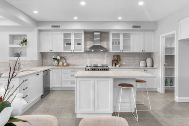 Large transitional l-shaped eat-in kitchen in Brisbane with an undermount sink, shaker cabinets, white cabinets, grey splashback, stainless steel appliances, with island, grey floor and grey benchtop.