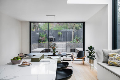 Photo of a large modern kitchen/diner in London with painted wood flooring and brown floors.