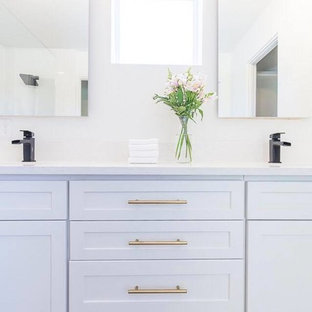 Esempio di una stanza da bagno padronale minimalista di medie dimensioni con ante in stile shaker, ante bianche, vasca da incasso, doccia ad angolo, WC a due pezzi, piastrelle bianche, piastrelle in ceramica, pareti bianche, pavimento in mattoni, lavabo da incasso e top in quarzo composito