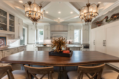 Inspiration for a large traditional u-shaped eat-in kitchen in Houston with a farmhouse sink, recessed-panel cabinets, white cabinets, quartzite benchtops, white splashback, marble splashback, panelled appliances, dark hardwood floors, multiple islands, brown floor and grey benchtop.