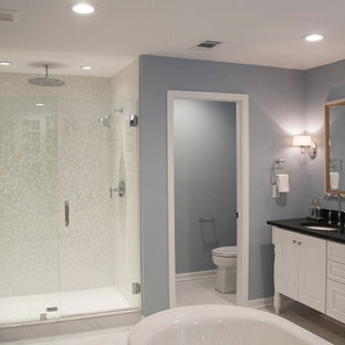 Aménagement d'une grande douche en alcôve principale classique avec un placard avec porte à panneau surélevé, des portes de placard blanches, une baignoire indépendante, un WC séparé, un carrelage beige, un carrelage blanc, des carreaux de porcelaine, un mur gris, un sol en carrelage de céramique, un lavabo encastré, un plan de toilette en granite, un sol gris et une cabine de douche à porte battante.